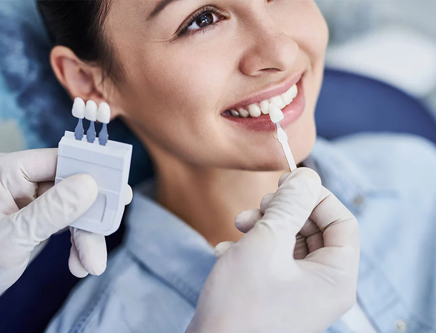 A patient smiling as her dentist matches the shade of her teeth